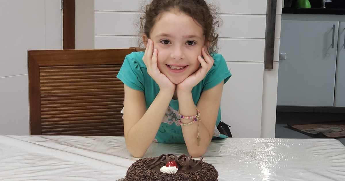 Livia, criança com diabetes tipo 1, sorrindo diante do bolo de aniversário