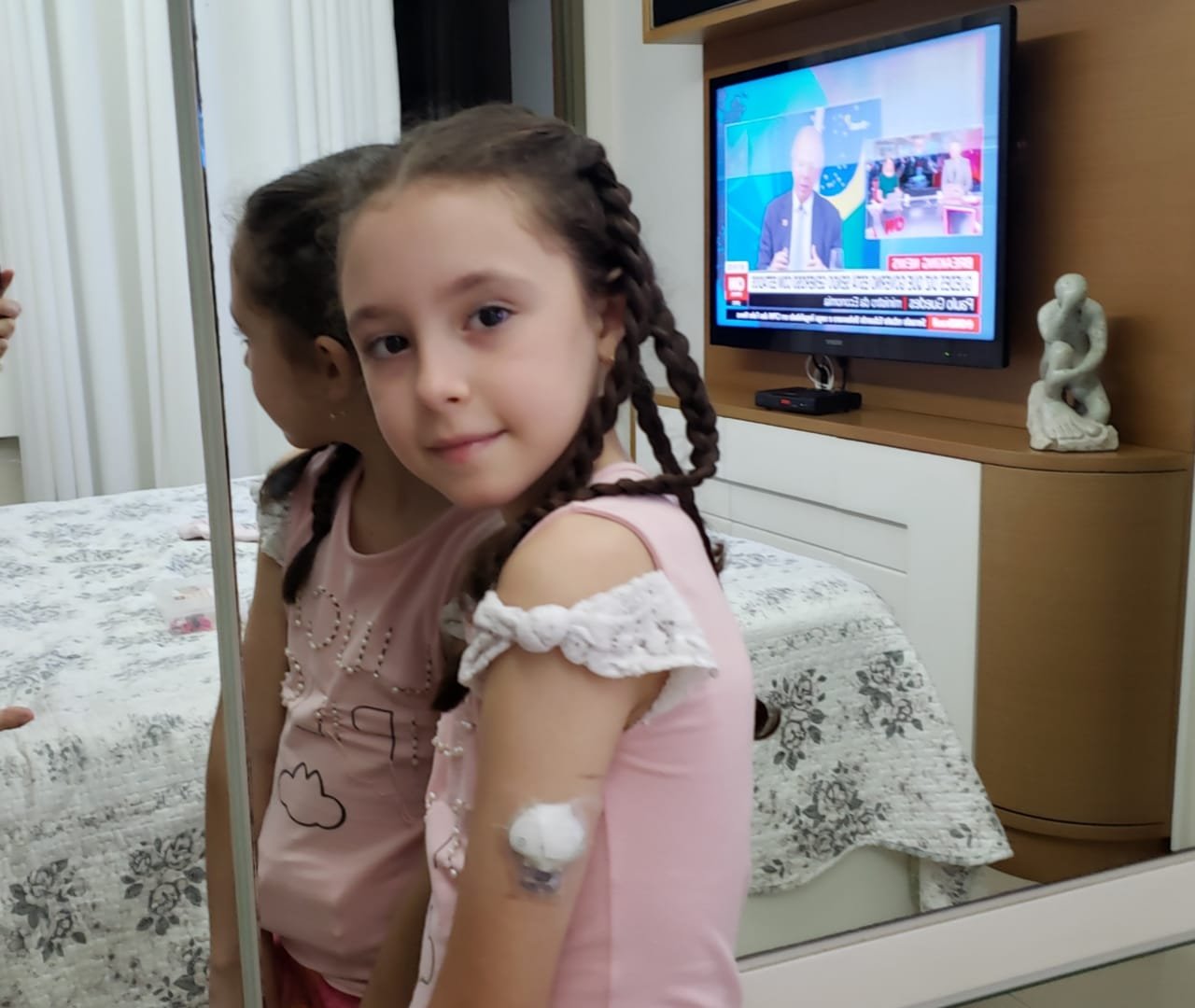 Livia, criança com diabetes tipo 1, mostrando o sensor de glicose no braço